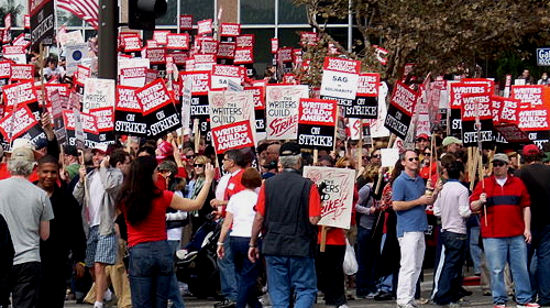 Writers Guild of America members on strike, holding WGA picket signs on a Hollywood street