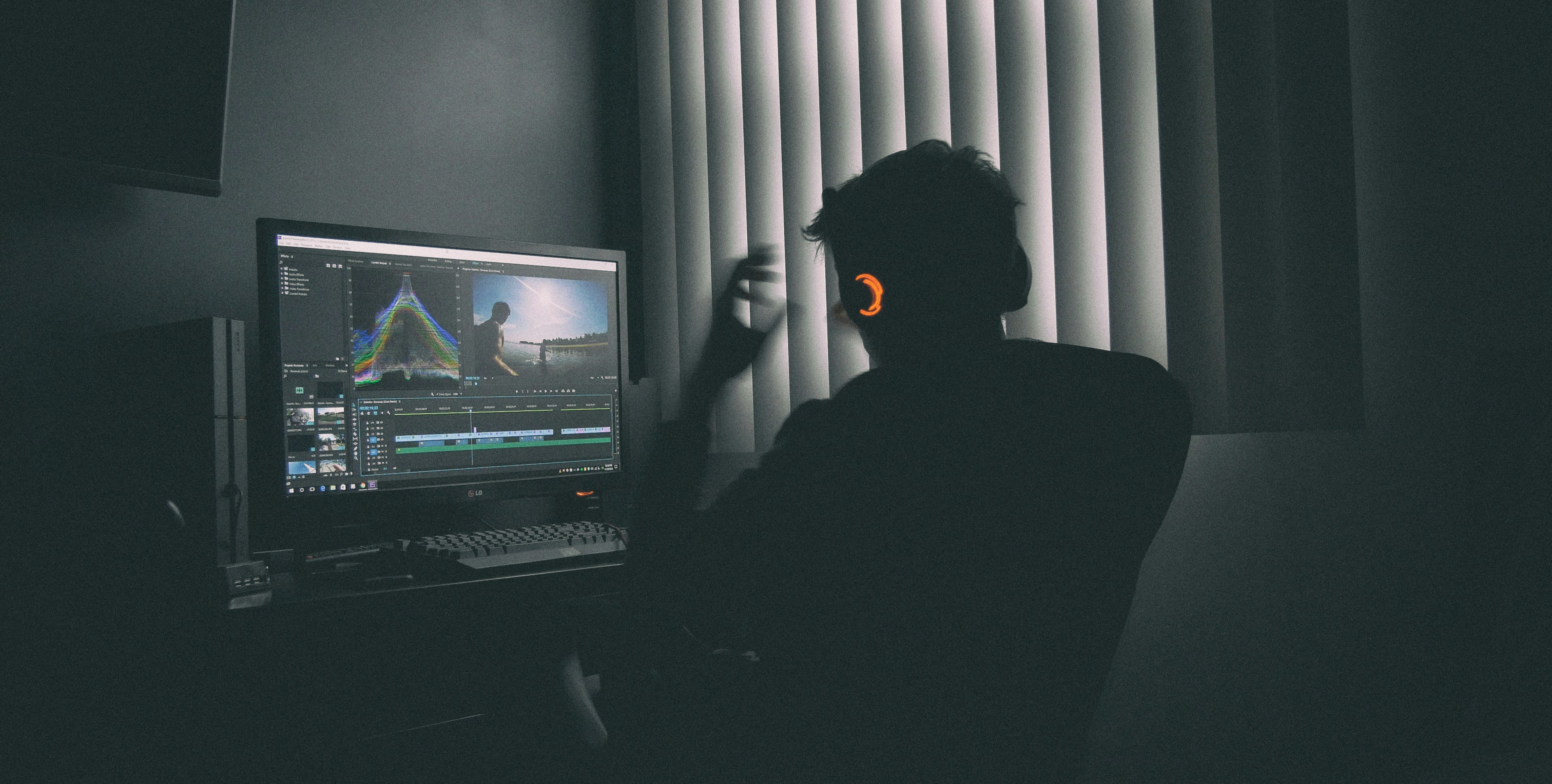 Person at a computer workstation with headphones, working at a desk