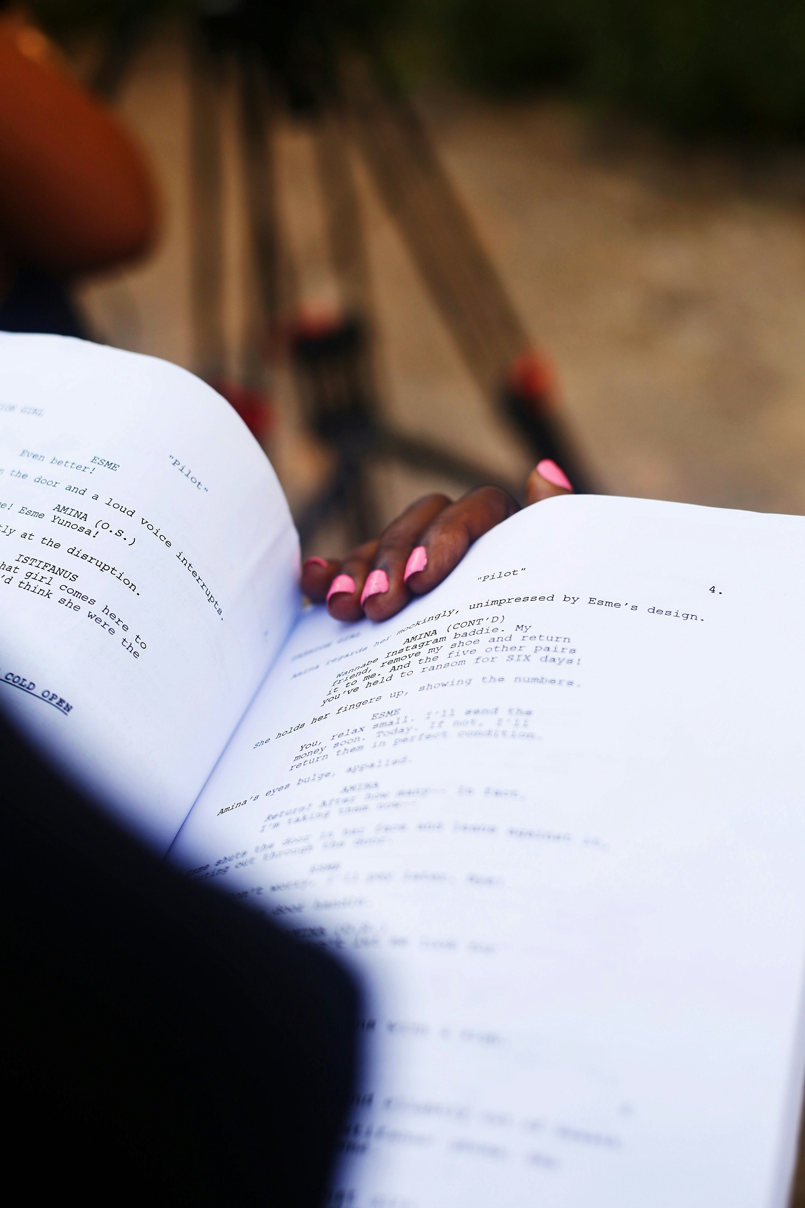 Hand resting on an open film script with a camera in the background