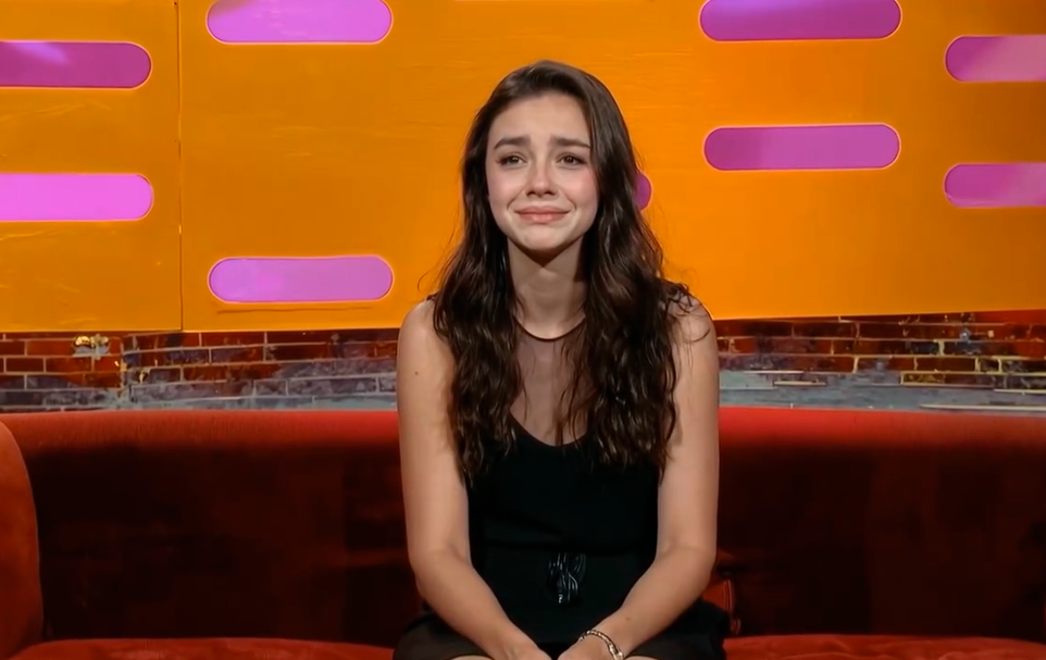 Tilly Norwood AI actress in interview setting with orange and purple background